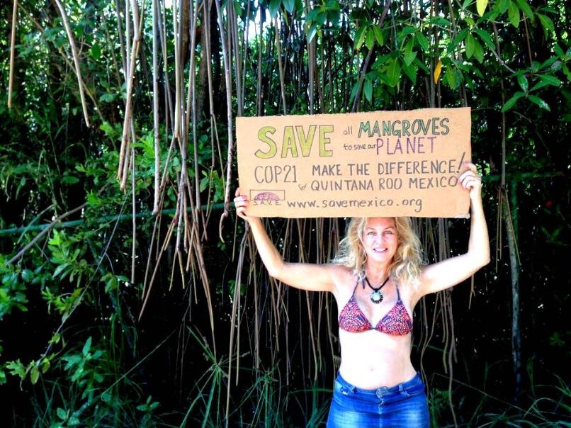 Activist holding a hand-painted sign in defense of the mangroves